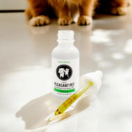 The Pleasant Pet CBD oil bottle with dropper and pet in background